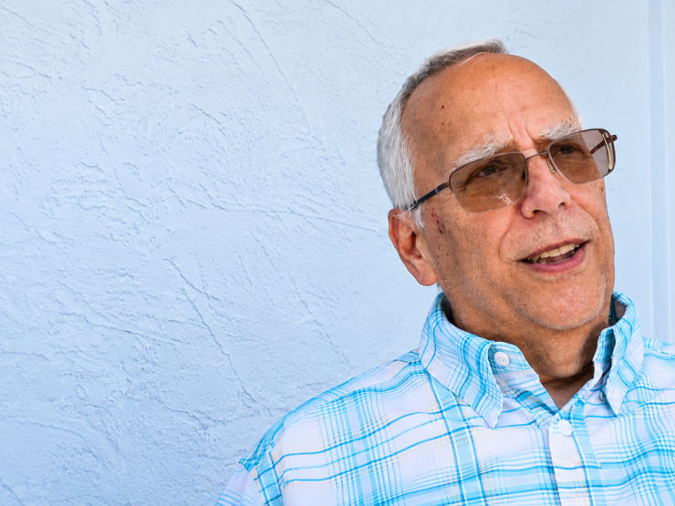 Thoughtful Elderly Man Gesturing by Blue Door.png