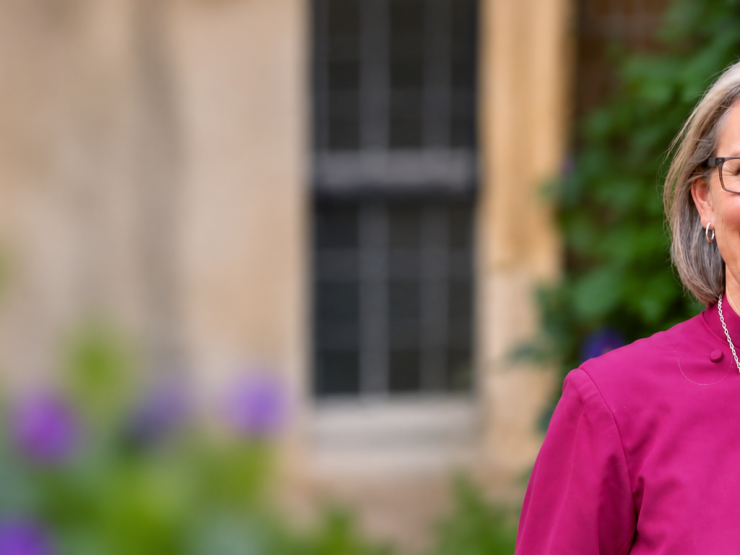 Smiling Clergywoman Among Purple Blooms.png